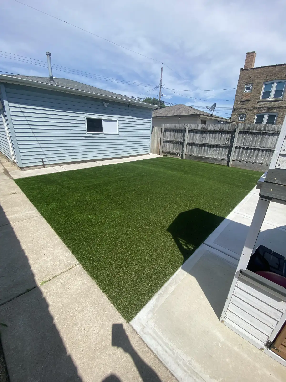 Compact residential yard finished with artificial turf and concrete borders