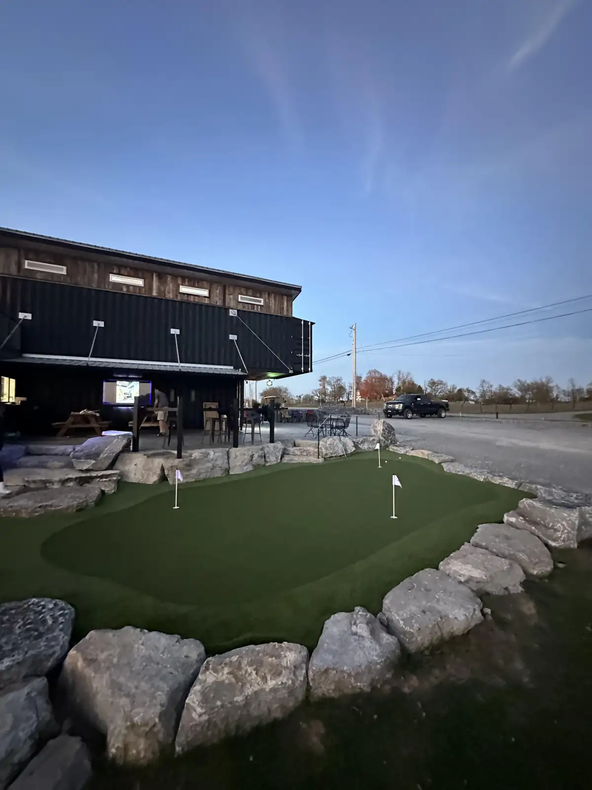 Commercial putting green next to rustic bar and restaurant with boulder border