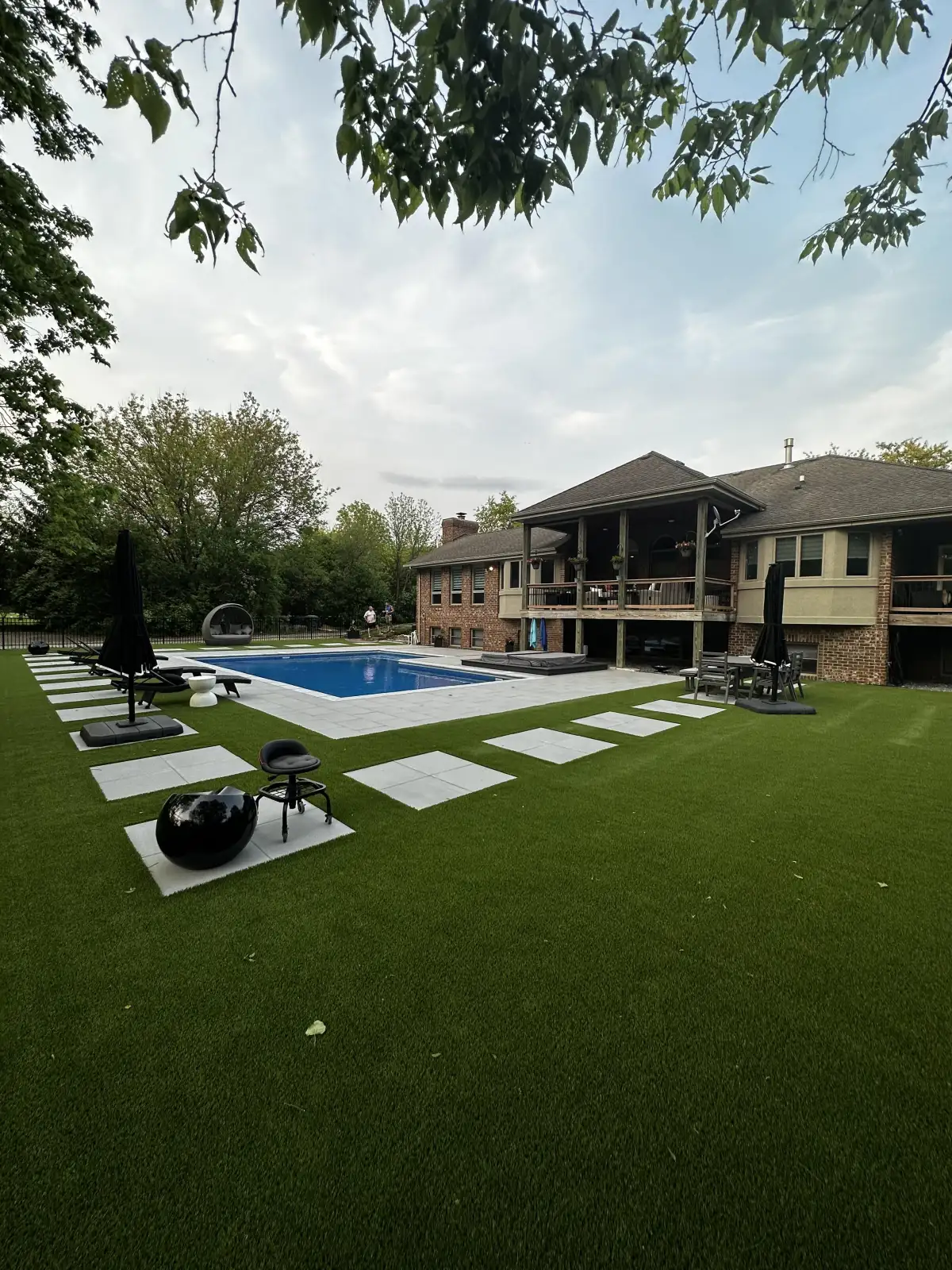 Luxury backyard with synthetic turf, pool, and stepping stones in Ann Arbor
