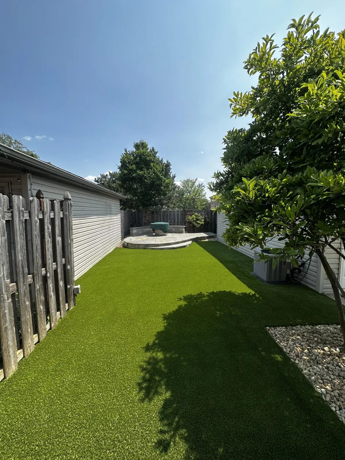 Sunny backyard with synthetic turf and shade tree near Muskegon