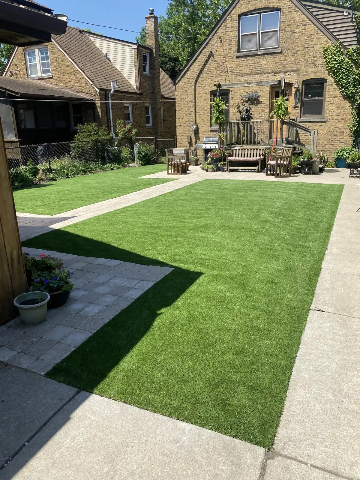 Large backyard with synthetic turf and paver walkway in the Lansing area