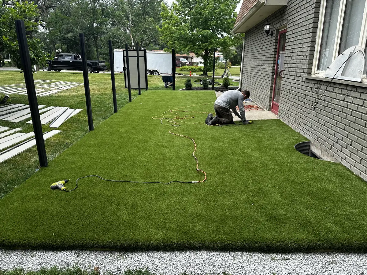 Great Lakes Synthetic Turf installer seaming turf on hands and knees showing craftsmanship