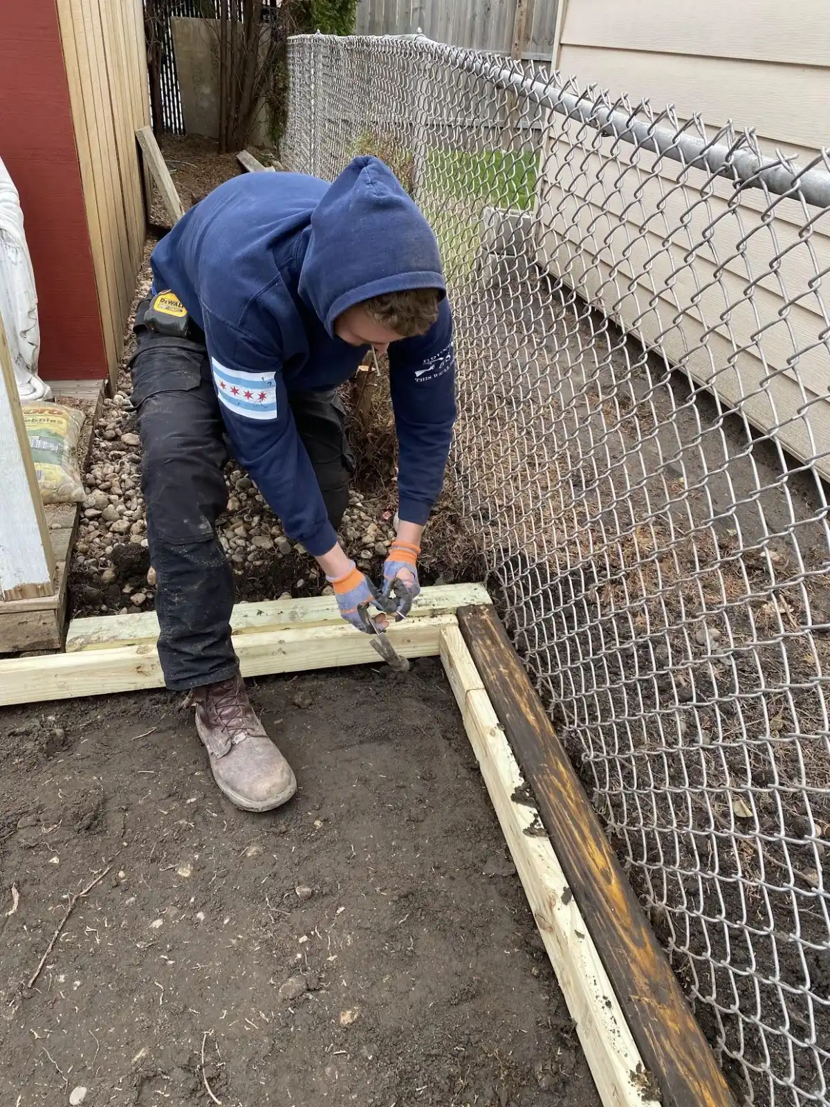 Installer fastening an edge frame beside a fence